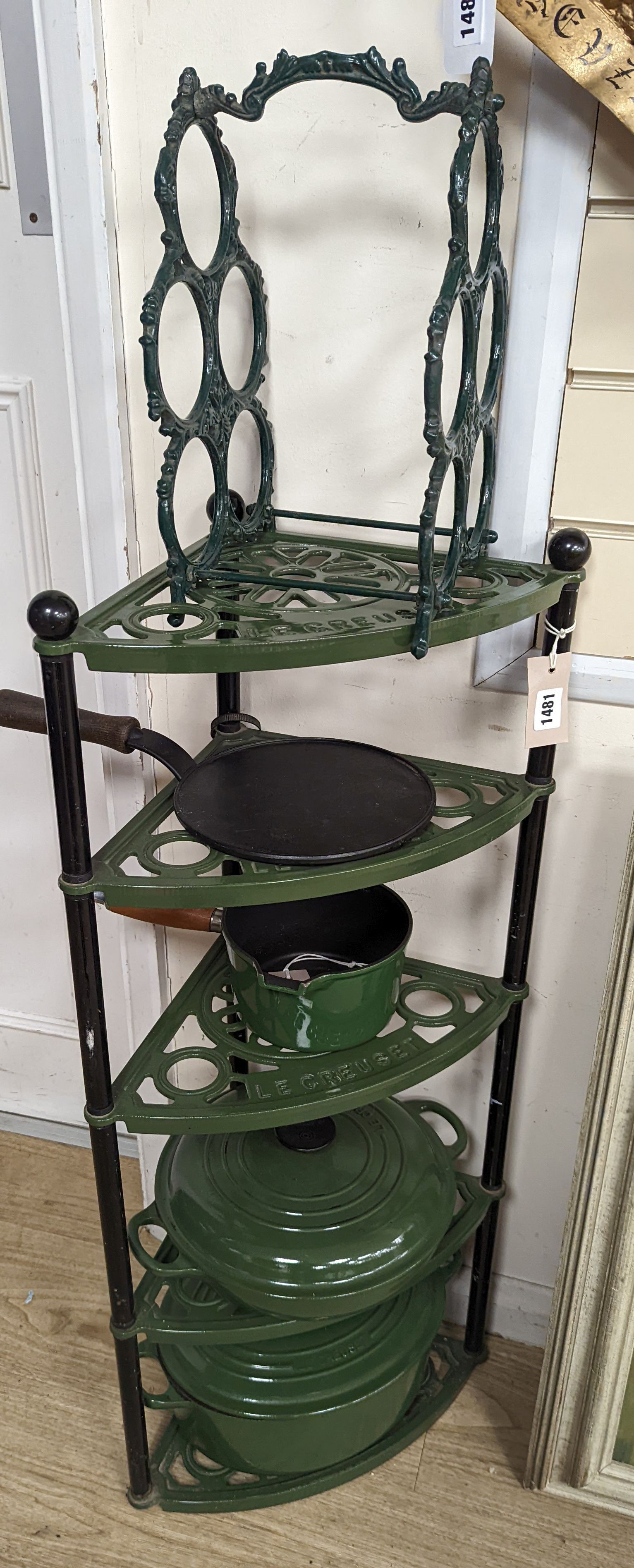 A green enamel Le Cruset pot stand, three pans and a bottle rack, stand 90 cms high.